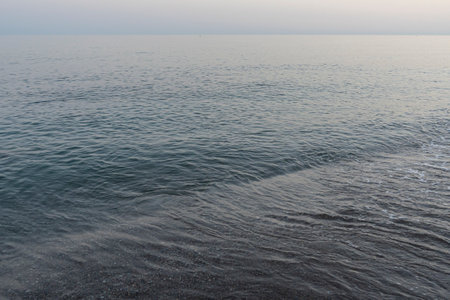 Gentle waves lap the shore at dusk on a tranquil beach in MÃ¡laga, Spain. Perfect for themes of relaxation, coastal serenity, and nature's beauty.の写真素材