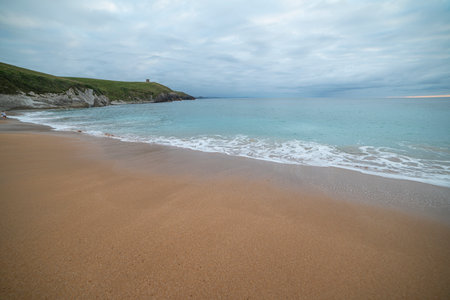 Tranquil scene of Tagle Beach in Cantabria, Spain, showcasing rugged rocks, gentle waves, and an expansive horizon. Perfect for travel, nature, and coastal themes.の写真素材