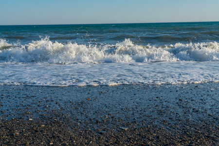 Powerful waves break along the shores of Malaga, Spain, with distant mountains visible on the horizon. Ideal for themes of coastal energy, nature, and scenic seascapesの写真素材