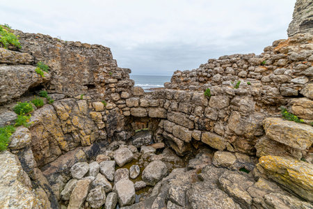 Captivating view of historic stone ruins perched on a rugged cliff in Cantabria, Spain, with the ocean in the background. Ideal for travel, history, and landscape themes.の写真素材