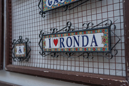 A close-up of a colorful "I Love Ronda" tile sign mounted on a rustic wall in Ronda, Spain. Ideal for themes of travel, local culture, and decorative arts in Spain.の写真素材