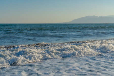 Powerful waves break along the shores of Malaga, Spain, with distant mountains visible on the...