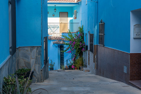 A picturesque view of JÃºzcar, the blue-painted village in Andalusia, Spain, bathed in morning sunlight. Perfect for travel brochures, cultural features, or serene landscape themes.の写真素材