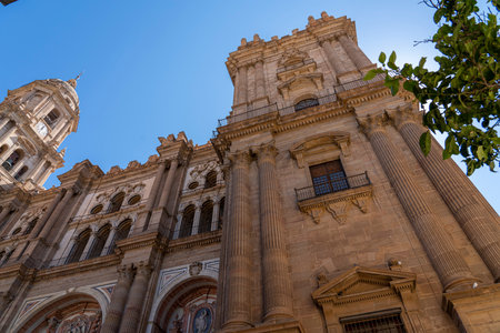 A striking view of the intricate facade of MÃ¡laga Cathedral, showcasing its grand architecture against a clear blue sky. Ideal for themes of historic landmarks, architecture, and Spanish heritage.の写真素材
