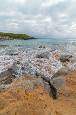 Tranquil scene of Tagle Beach in Cantabria, Spain, showcasing rugged rocks, gentle waves, and an expansive horizon. Perfect for travel, nature, and coastal themes.の写真素材
