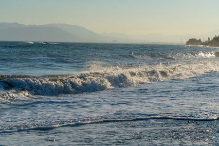 Powerful waves break along the shores of Malaga, Spain, with distant mountains visible on the horizon. Ideal for themes of coastal energy, nature, and scenic seascapesの写真素材