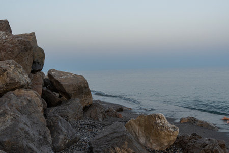 Gentle waves lap the shore at dusk on a tranquil beach in MÃ¡laga, Spain. Perfect for themes of relaxation, coastal serenity, and nature's beauty.の写真素材