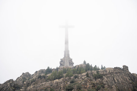 Valley of the Fallen: Iconic Cross Surrounded by Misty Mountainsの写真素材