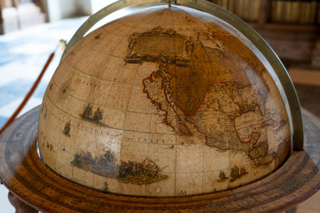 A detailed globe illustrates old world maps, featuring North and South America prominently. It is...