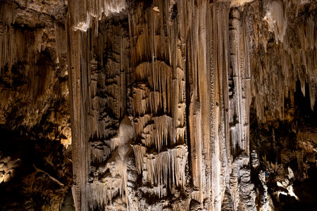 The interior of the caves in MÃ¡laga features impressive stalactites and stalagmites, illuminated to highlight the textures and shapes of the ancient rock formations.の写真素材