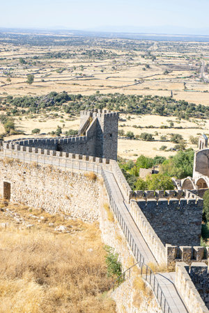 Visitors hike along the ancient castle walls of Trujillo in Extremadura, Spain, enjoying breathtaking views of the rural landscape and historical architecture under a clear sky.の写真素材