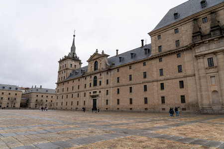 Visitors stroll across the expansive stone courtyard of Monasterio de El Escorial, admiring the...