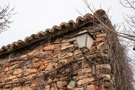 Stone wall with a lamp and vines.. Pueblo de Patones de Arriba in Madrid, known for its slate architecture and for evading the French invasion., roofの写真素材