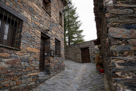 Narrow stone street with rustic buildings and greenery.. Pueblo de Patones de Arriba in Madrid, famous for its slate architecture and for evading the French invasion., doorの写真素材