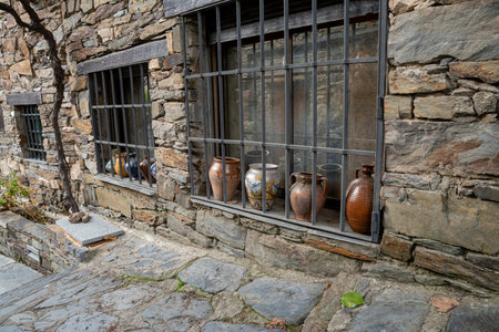 Stone wall with barred windows and pottery.. Pueblo de Patones de Arriba in Madrid, famous for its slate architecture and for evading the French invasion., jarsの写真素材