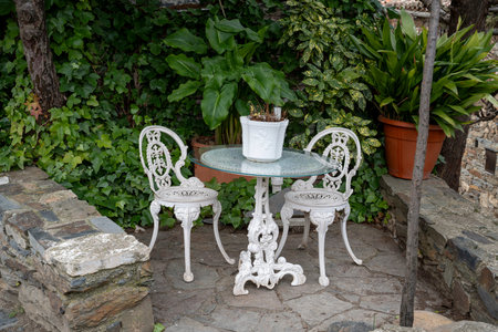 White table and chairs surrounded by greenery.. Patones de Arriba, Madrid. A village made of slate., plantsの写真素材