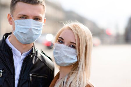 Young couple in masks on city street. Isolation, quarantine.の写真素材