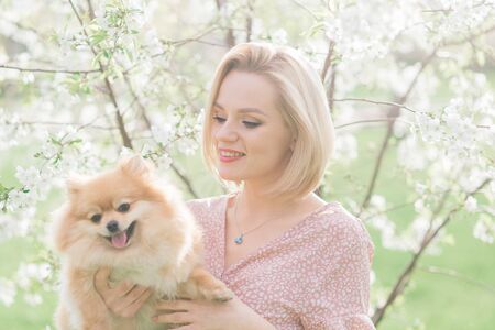 Close up portrait of smiling young attractive woman embracing Pomeranian spitz.の写真素材
