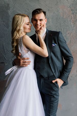 Cute wedding couple in the interior of a classic studio. They kiss and hug each other.の写真素材