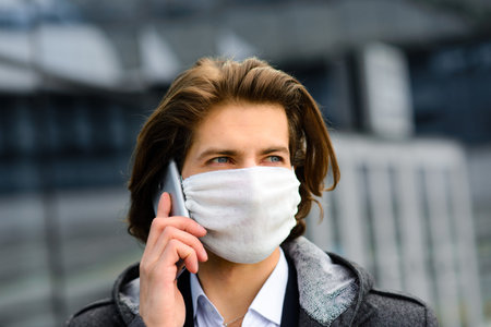 Young man in a medical mask outside looking for a job.