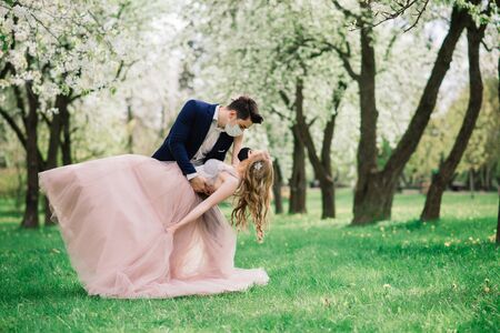 Young loving couple walking in medical masks in the park during quarantine on their wedding day. Coronavirus, disease, protection, sick. Europe celebration canceled.の写真素材