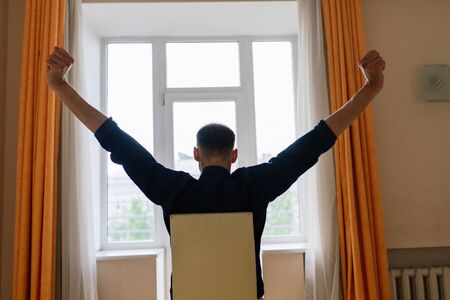 Relaxed young man resting from work. Man enjoy break stretching in home office workplaceの写真素材