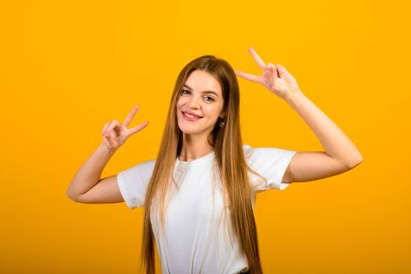 Isolated portrait of happy woman has toothy smile, closes eyes, feels pleasure from good compliment, stands over yellow wall. Positive emotions and feelings conceptの写真素材