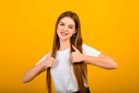 Isolated portrait of happy woman has toothy smile, closes eyes, feels pleasure from good compliment, stands over yellow wall. Positive emotions and feelings conceptの写真素材