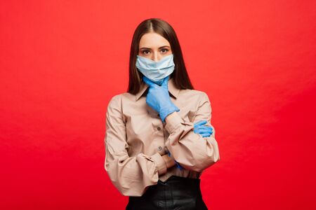 Emotional female in medical mask and gloves. Pandemic coronavirus epidemic covid-19 quarantine isolated redの写真素材