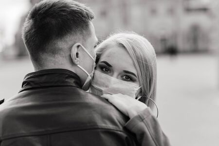 Young couple in love in protective medical mask on face outdoor at street. Guy and girl in virus protection.の写真素材