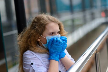 Portrait of sad caucasian child in face mask on closed playground outdoor. Coronavirus social distance quarantine.の写真素材