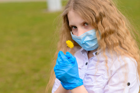 Portrait of sad caucasian child in face mask on closed playground outdoor. Coronavirus social...