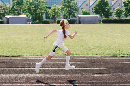 Girl jogging on a sunny summer evening, laying on treadmill, stadium, physical training, back to school, tired.の写真素材