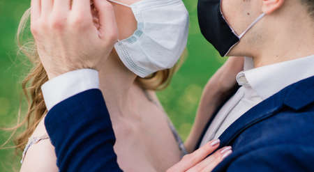 Young loving couple walking in medical masks in the park during quarantine on their wedding day. Coronavirus, disease, protection, sick. Europe celebration canceled.の写真素材