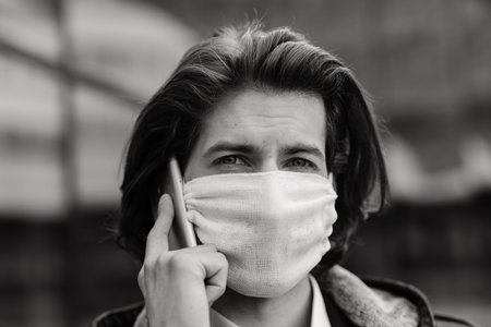 Young man in a medical mask outside, no money, poverty, hardship. Quarantine, isolation.の写真素材
