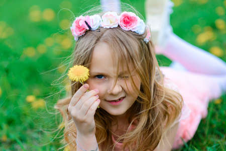 Pretty child girl smiling and playing in flowers of the garden, blooming trees, cherry.の写真素材