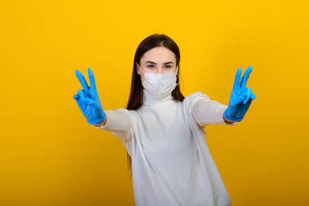 Girl in medical gloves dress a medical mask on her face on a background. Respiratory disease. Covidの写真素材
