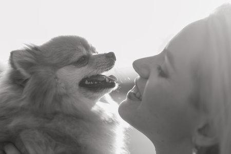 Close up portrait of smiling young attractive woman embracing Pomeranian spitz.