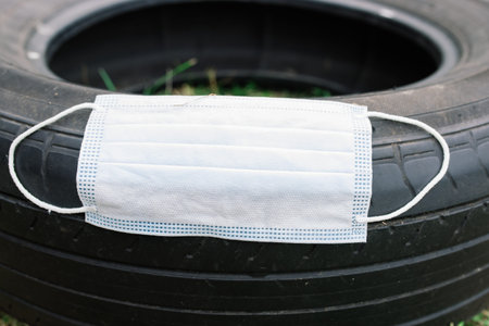 Medical face mask on tire of automobile, coronavirus conception