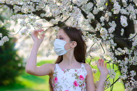 Lonely teenage girl wearing protection medicine mask against virus covid and allergy enjoying spring...