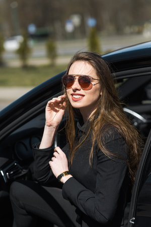 Young businesswoman in black wear with expensive car