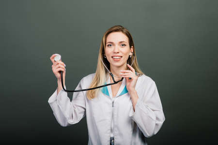 Portrait of woman doctor with stethoscope looking at camera on grey background, healthcareの写真素材