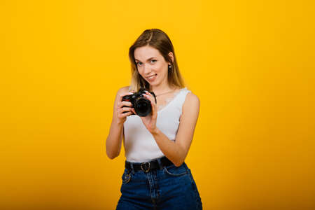 Excited female photographer working in studio. Portrait of stunning blonde girl with camera.の写真素材