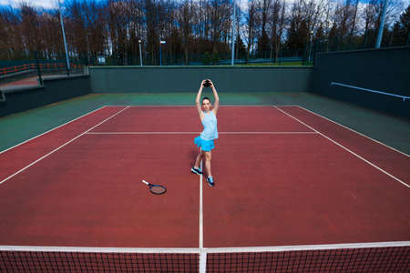 Sensual woman with tennis racket at net on lawn. Activity, energy, power. Sport, training, workout. Wellness, bodycare healthの写真素材