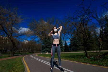 Cute girl in long white wedding dress posing in rural path among autumnal trees in forest in golden hourの写真素材