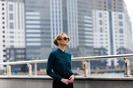 Young beautiful businesswoman with sunglasses, phone, laptop, cup of coffee in the city street