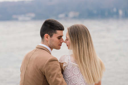 Salo, Italy - 02.02.2020. Romantic young couple sitting on the river dock and walking on the lake bank.のeditorial素材