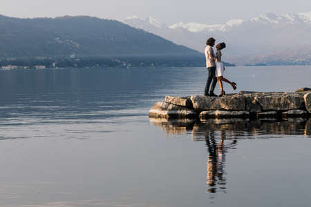 Milan, Italy - 02.04.2020. Young adult interracial couple on a beach, Caucasian man and African American female in casual clothes enjoying summer day on a sea shoreのeditorial素材