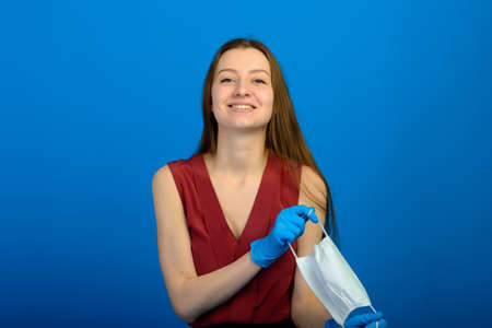 Portrait of a girl in a mask, which puts on a rubber glove. Yellow and red background.の写真素材