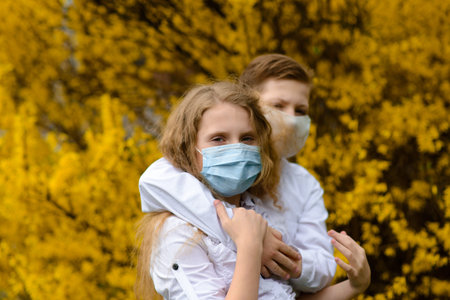 Children in a city park in a medical mask. Walking on the street during the quarantine period of the coronavirus pandemic in the Europe. Precautions and teaching childrenの写真素材